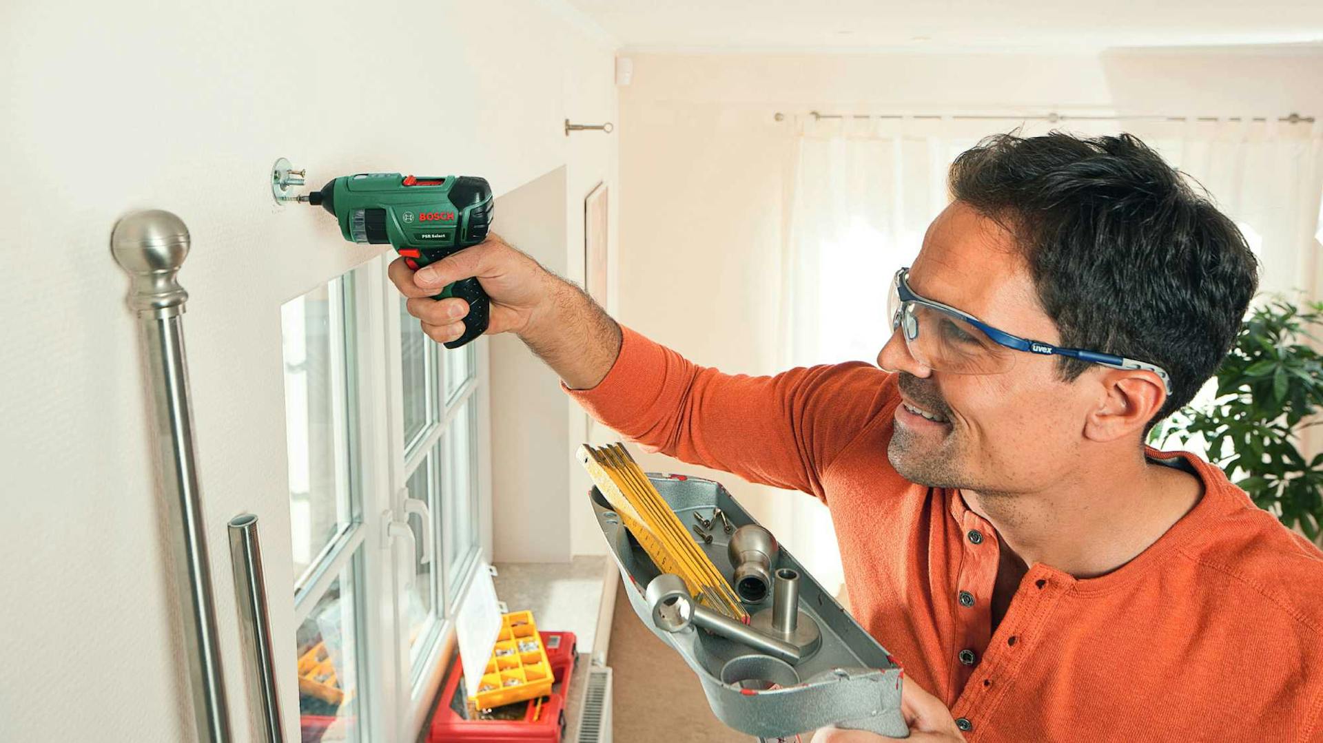 Mann bringt Gardine an