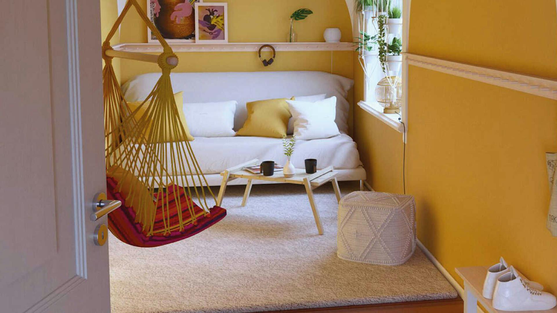 In einem gelb gestalteten Raum steht an der hinteren Wand eine helle Couch mit weißen und gelben Kissen. Davor sind Couchtisch Philip und ein weißer Pouf platziert und ein Hängesessel angebracht.