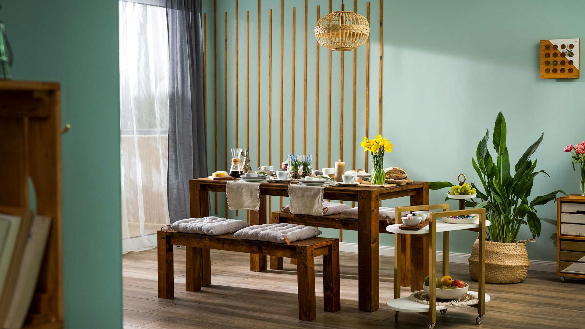 Tisch Maren aus dunklem Holz ist feierlich zu Ostern gedeckt und steht vor einer Wand, die mit Leisten gestaltet worden ist.