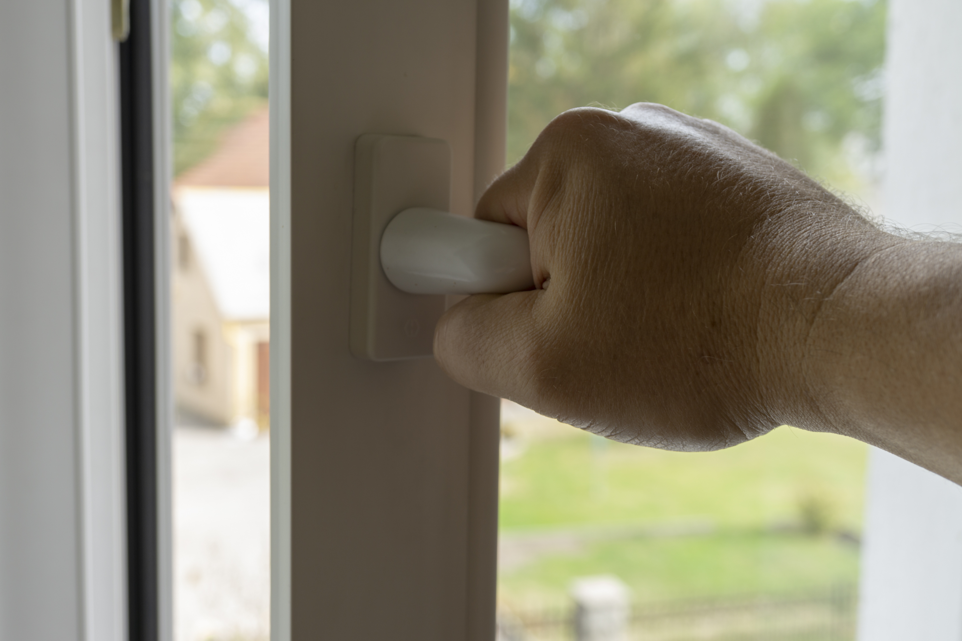 Eine Person öffnet ein Fenster.