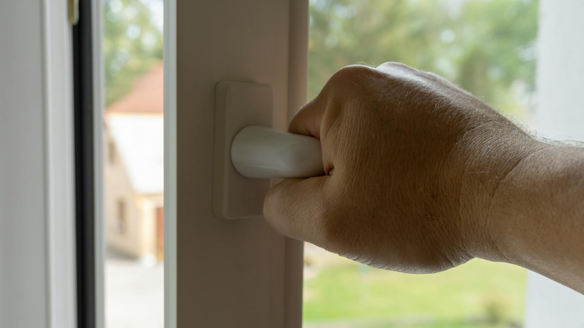 Eine Person öffnet ein Fenster.