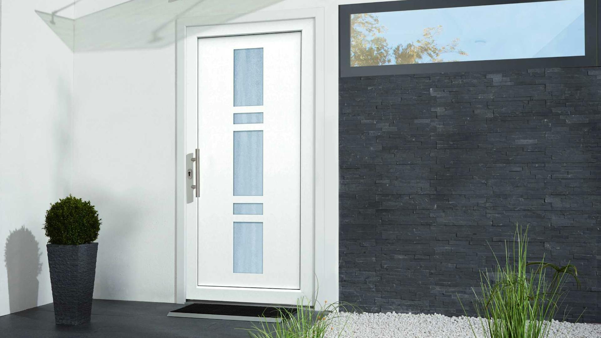Weiße Haustür mit Glaseinsatz neben dunkel verklinkerter Wand