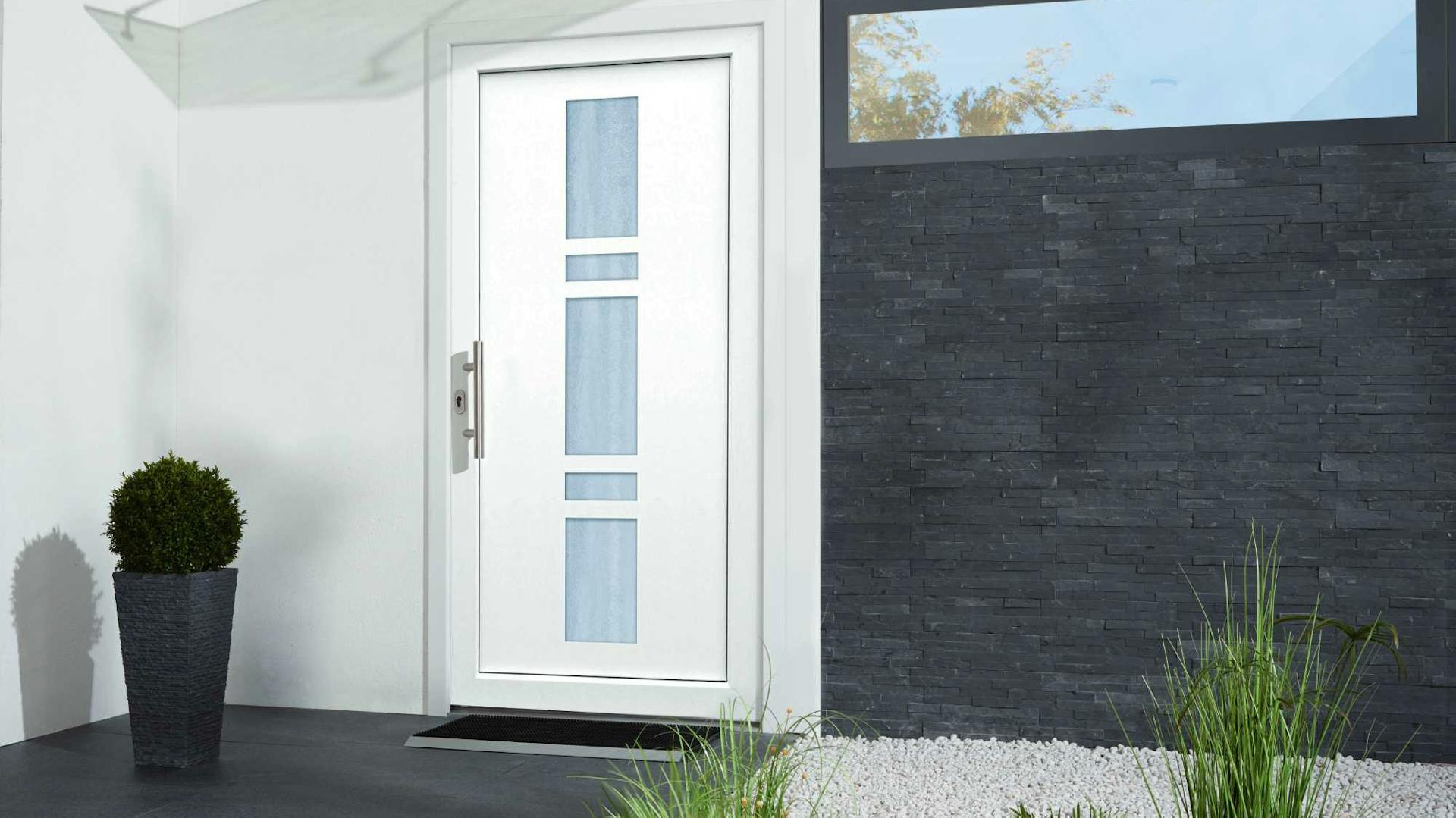 Weiße Haustür mit Glaseinsatz neben dunkel verklinkerter Wand