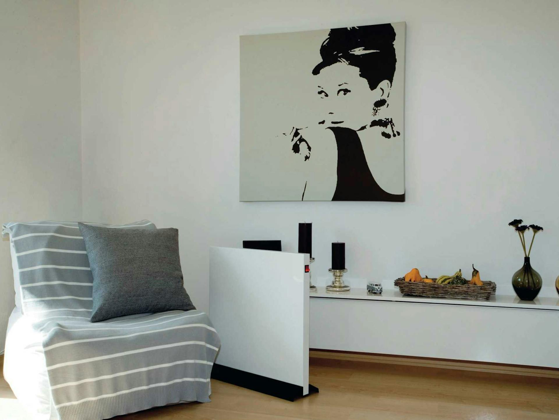 Radiatore elettrico indipendente accanto a una poltrona in una stanza luminosa