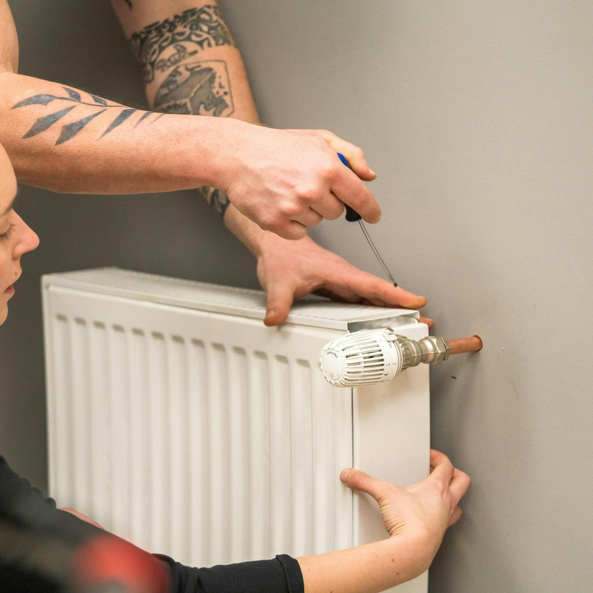 Két ember eltávolítja a fűtőtest fedelét.