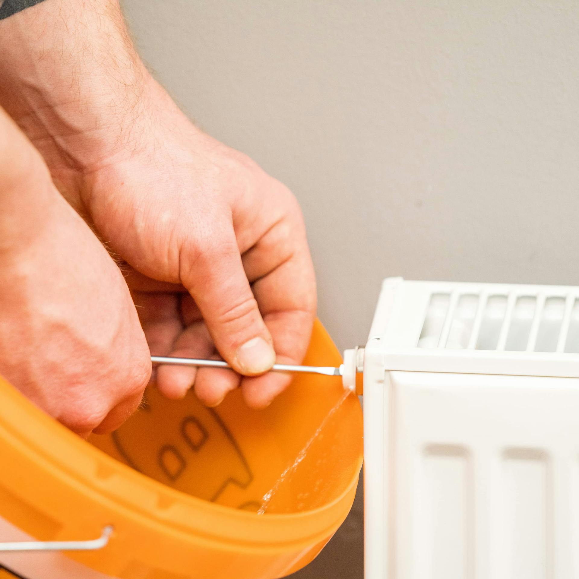 A férfi kinyitja egy fűtőszelepet.