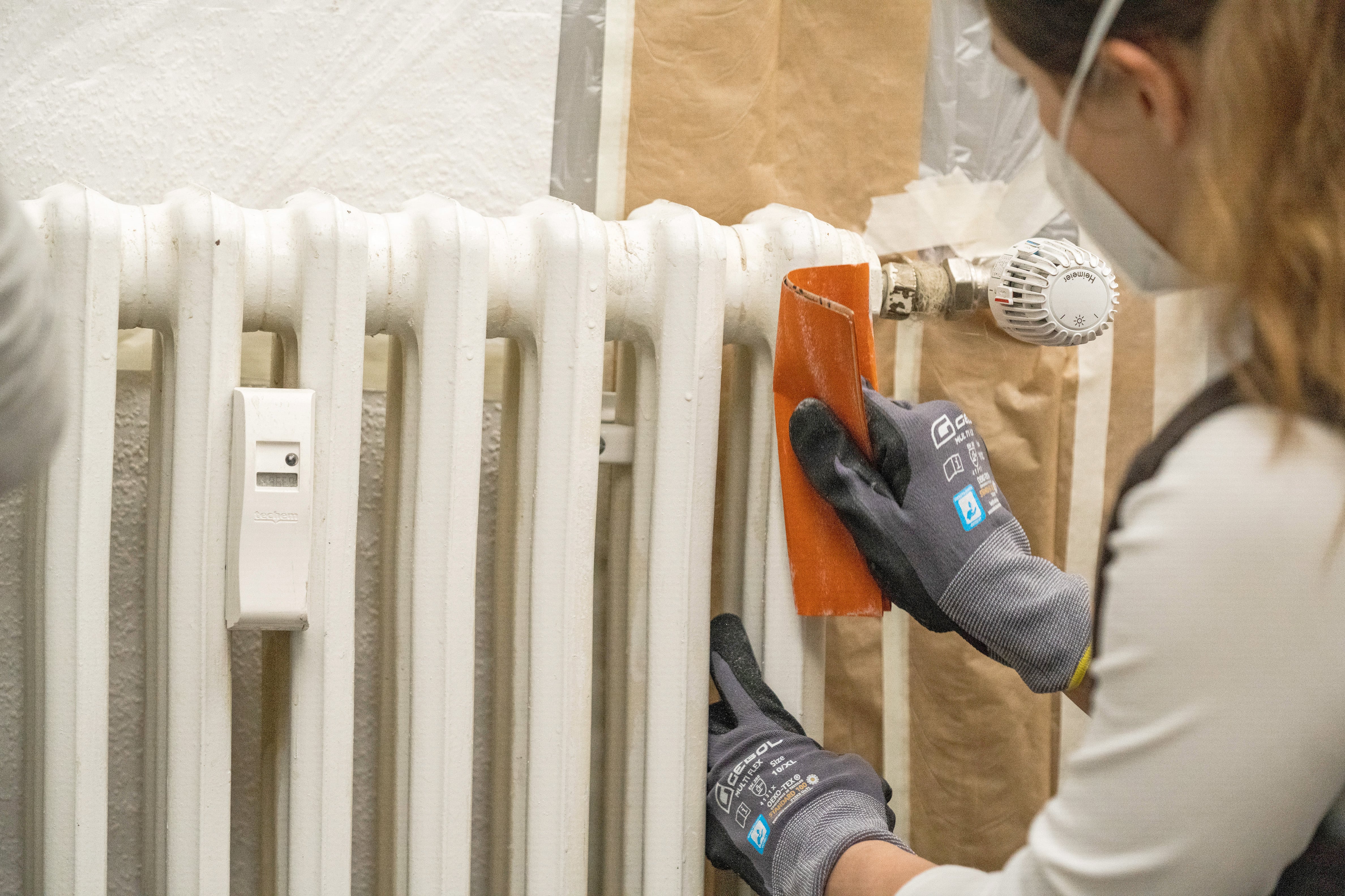 Egy barkácsoló nő lecsiszolja a radiátort.