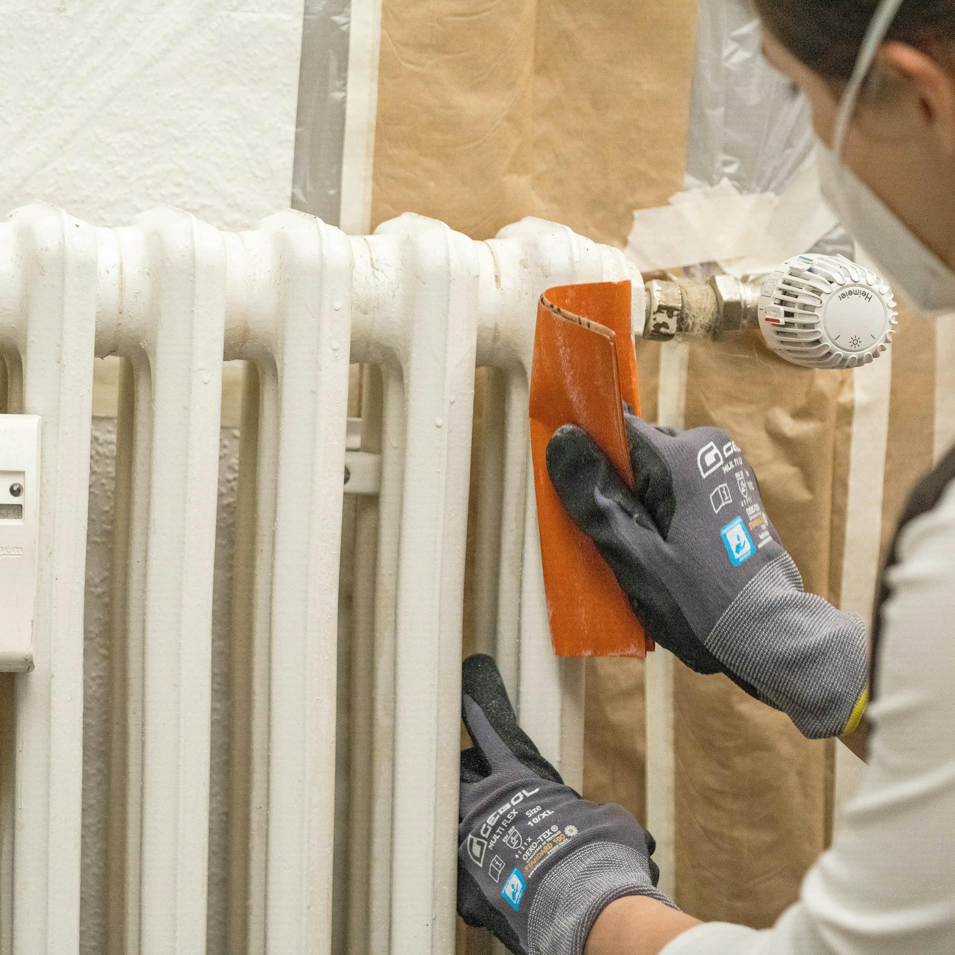 Egy barkácsoló nő lecsiszolja a radiátort.