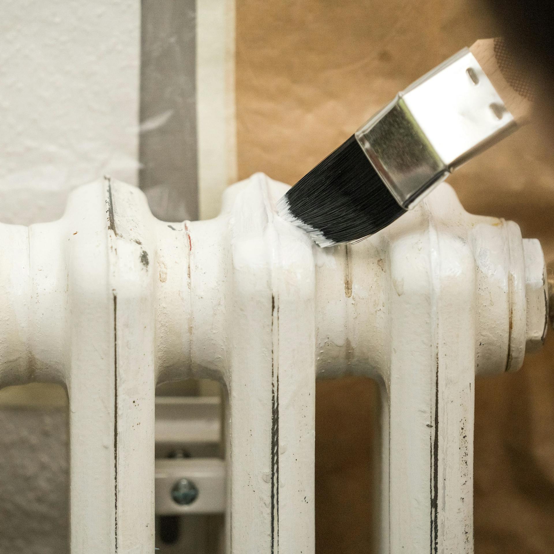 Egy barkácsoló alapozó festékkel keni le a radiátort.