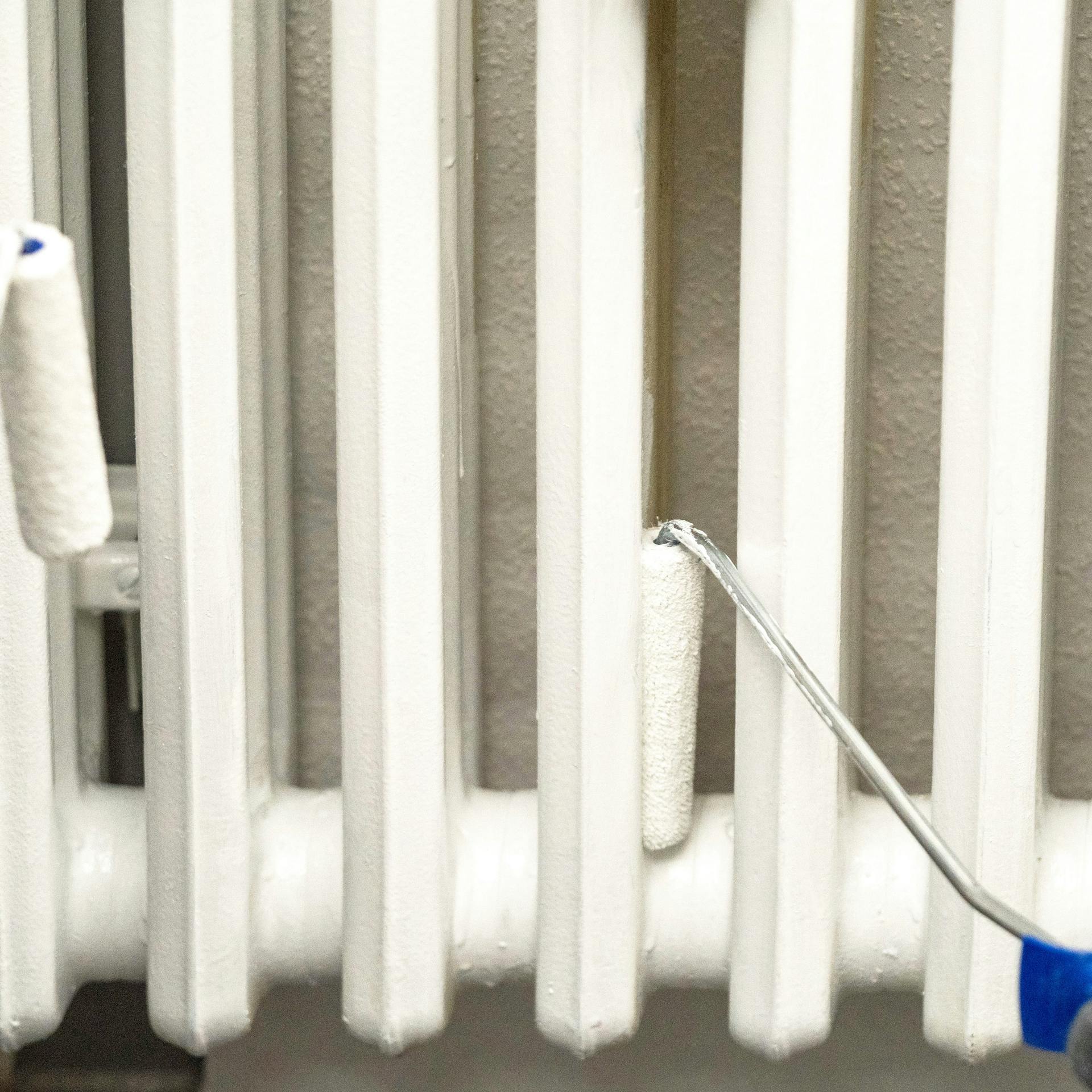 Két barkácsoló egy radiátort fest.