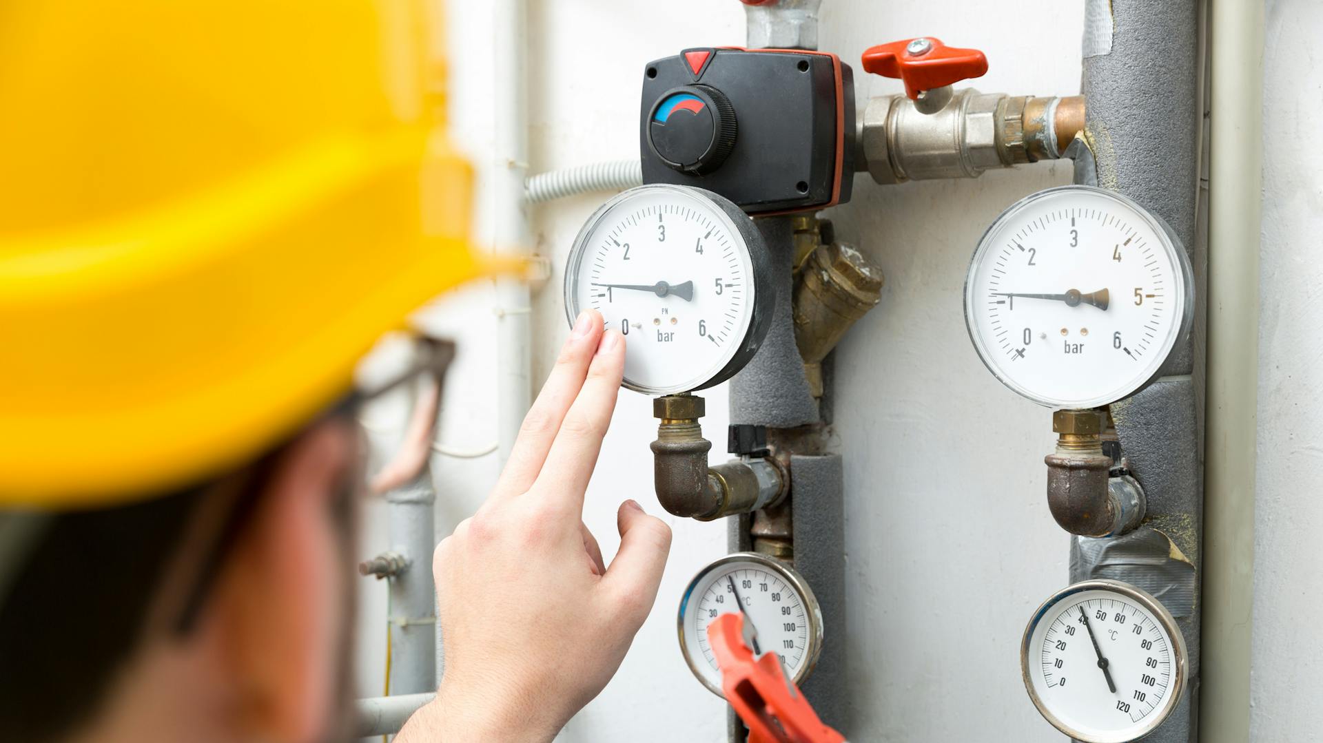 Person prüft Wasserdruck in Heizungsrohren.