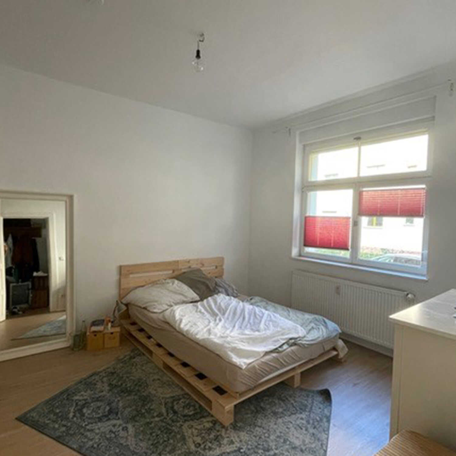 Einfaches Schlafzimmer mit einem Bett und einem dunklem Teppich. 