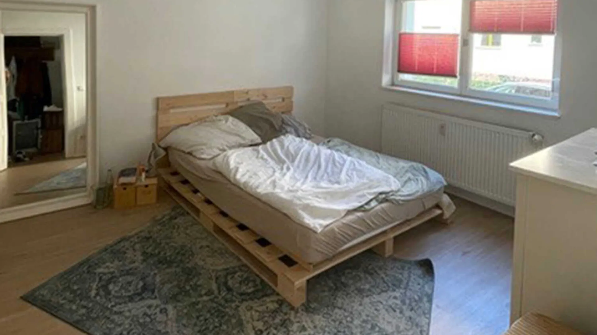 Einfaches Schlafzimmer mit einem Bett und einem dunklem Teppich.