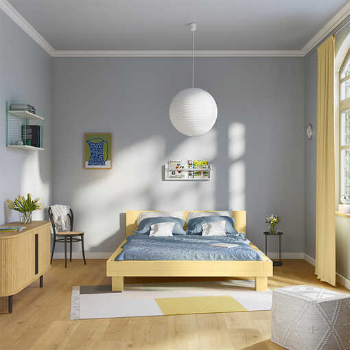 Bett Ludwig, welches in einem leichten gelb gestrichen worden ist steht vor einer pastellblauen Wand an der ein Magazinregal angebracht worden ist.