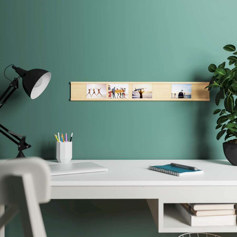 Eine Bilderleiste an einer grünen Wand über einem Schreibtisch