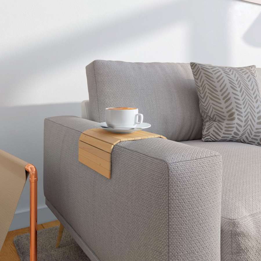 Ein Sofatablett, auf dem ein Kaffee steht, liegt auf der Armlehne eines grauen Sofas