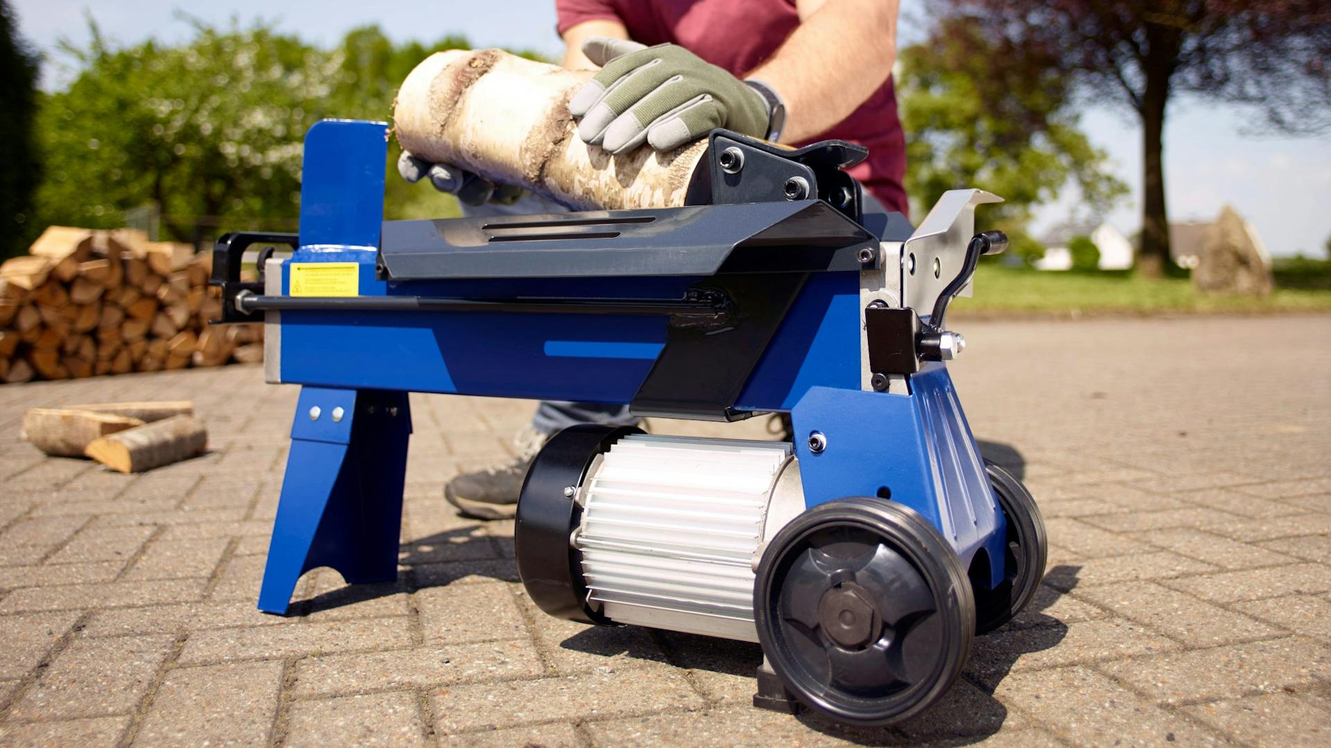 Jemand legt Holz in einen Holzspalter ein.