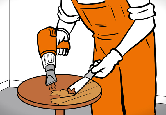 Hände mit Heißluftföhn und Spachtel auf Holztisch