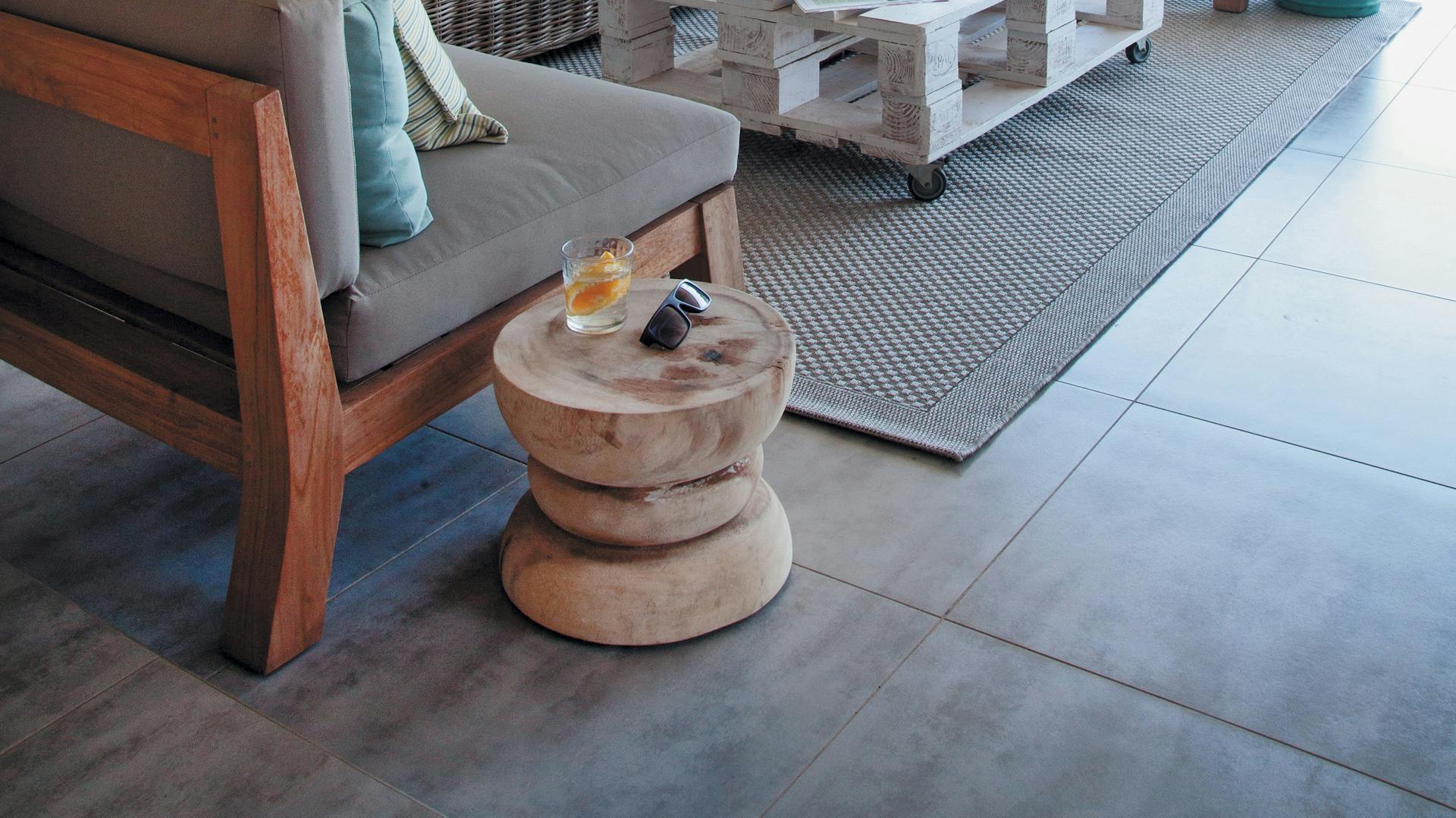 Sitzgarnitur aus Vollholz und Rattan vor breiter Fensterfront.