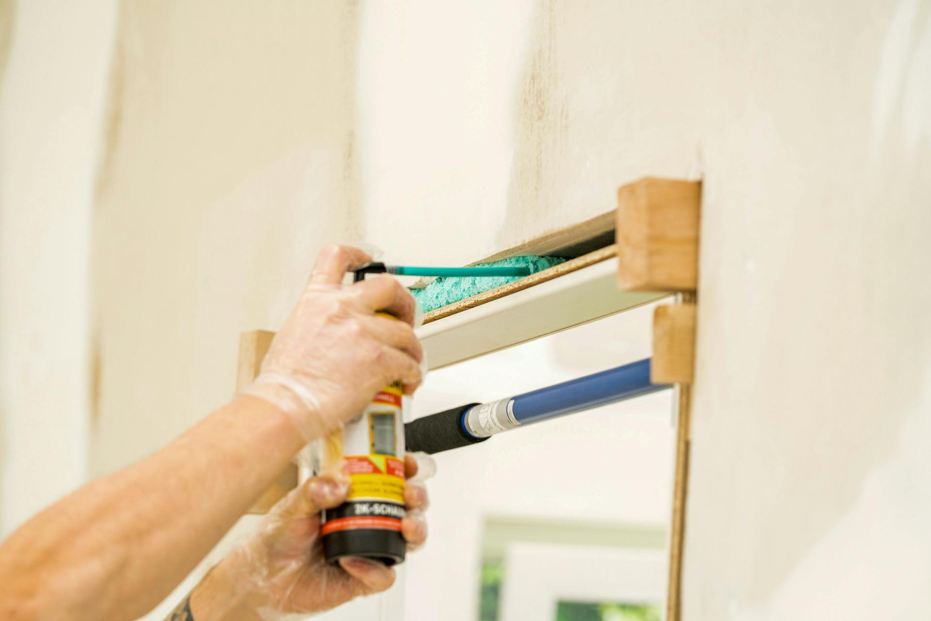 Pracovník vypĺňa zárubňu dverí penou na zárubne.