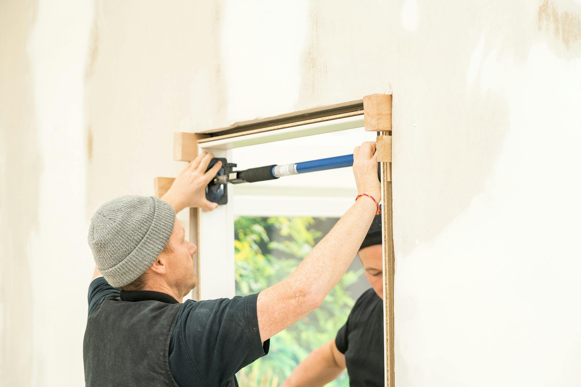 Pracovník upevňuje zárubňu pomocou vyrovnávacích klinov.