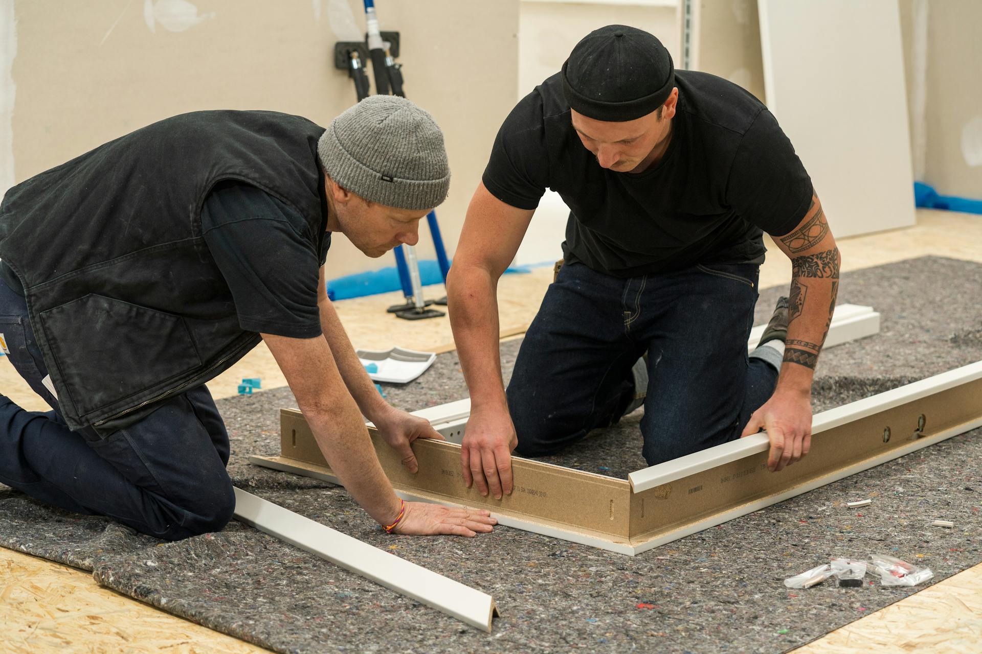 Pracovník montuje zárubňu dverí na podlahu.