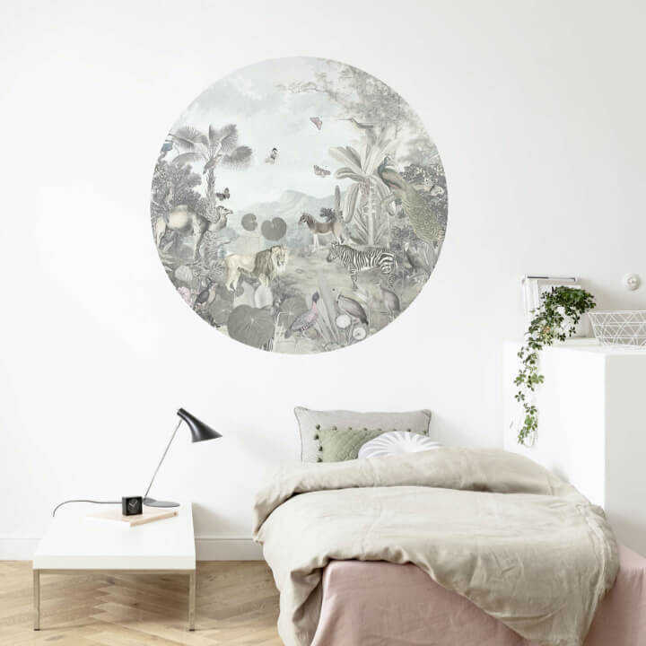 An der Wand, die sich hinter einem Bett und einem tiefen Ablagetisch befindet, klebt eine runde Tapete mit Dschungelmotiv mit Tieren an der Wand.