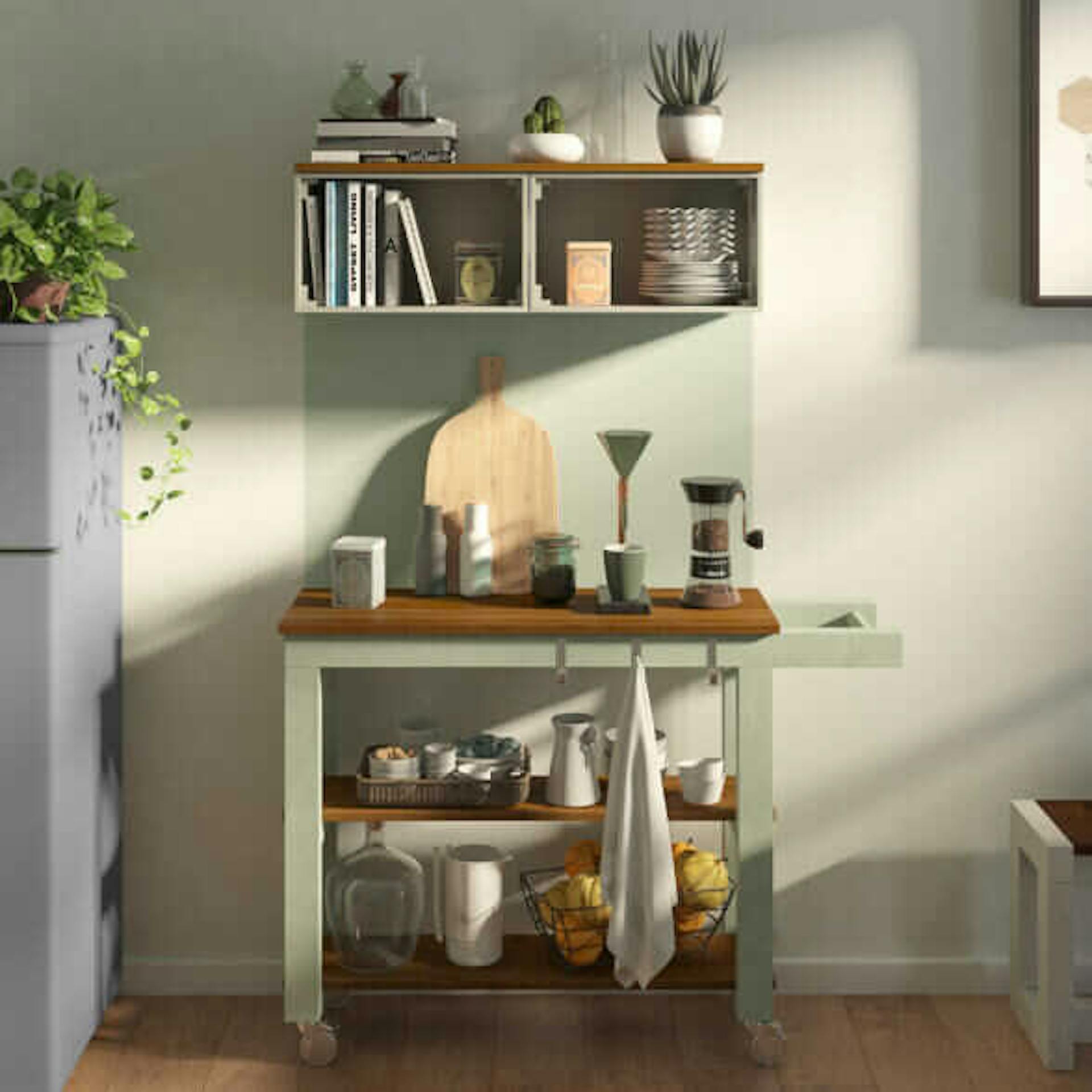 Ein pastellgrüner Servierwagen steht vor einer Wand mit pastellgrüner Farbfläche.