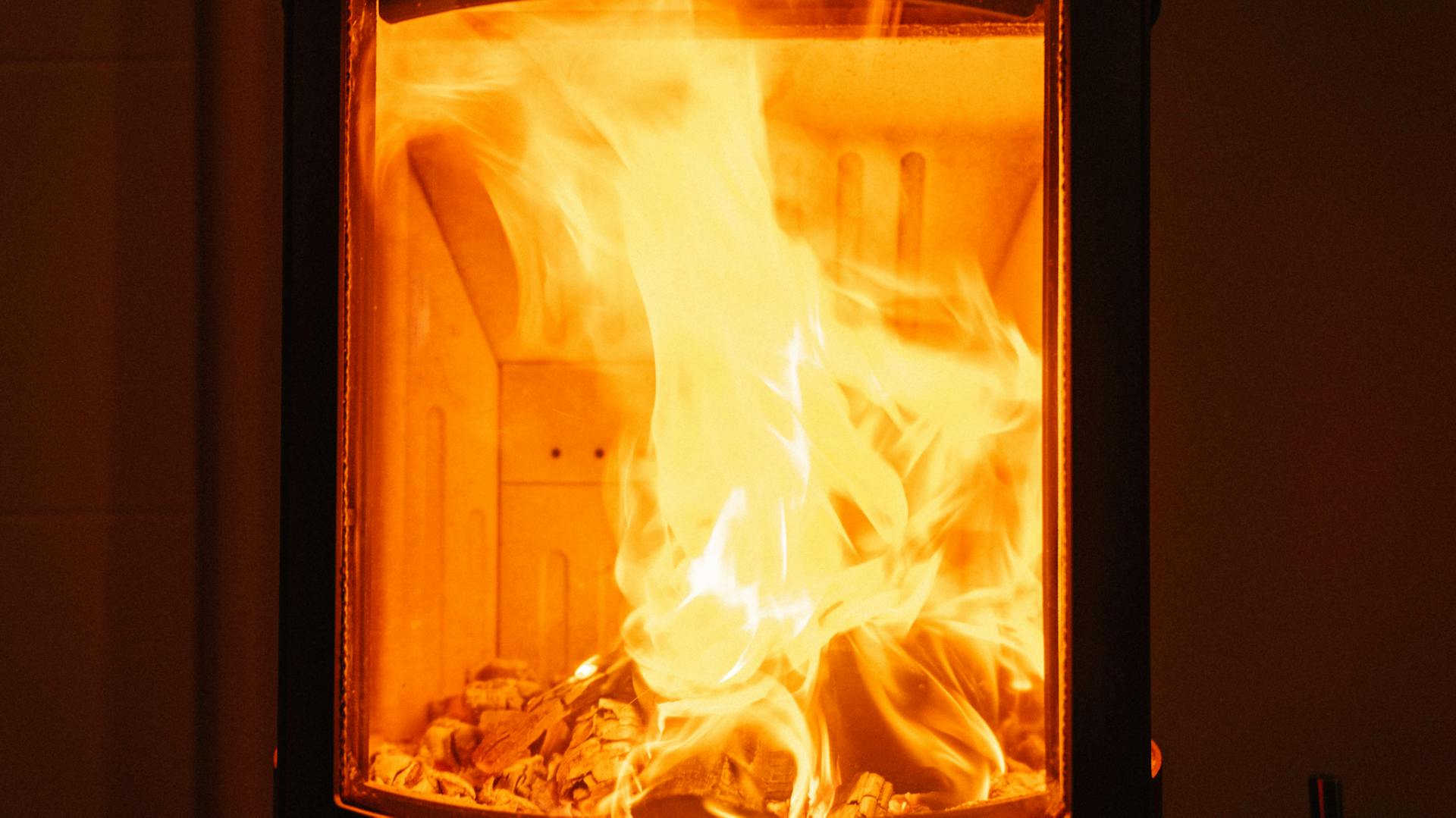 Fuoco ardente dietro la finestra di vetro della stufa caminetto