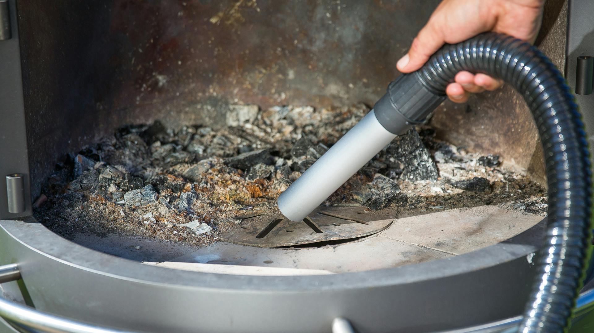 Mit einem Aschesauger wird der Kamin gesaugt.