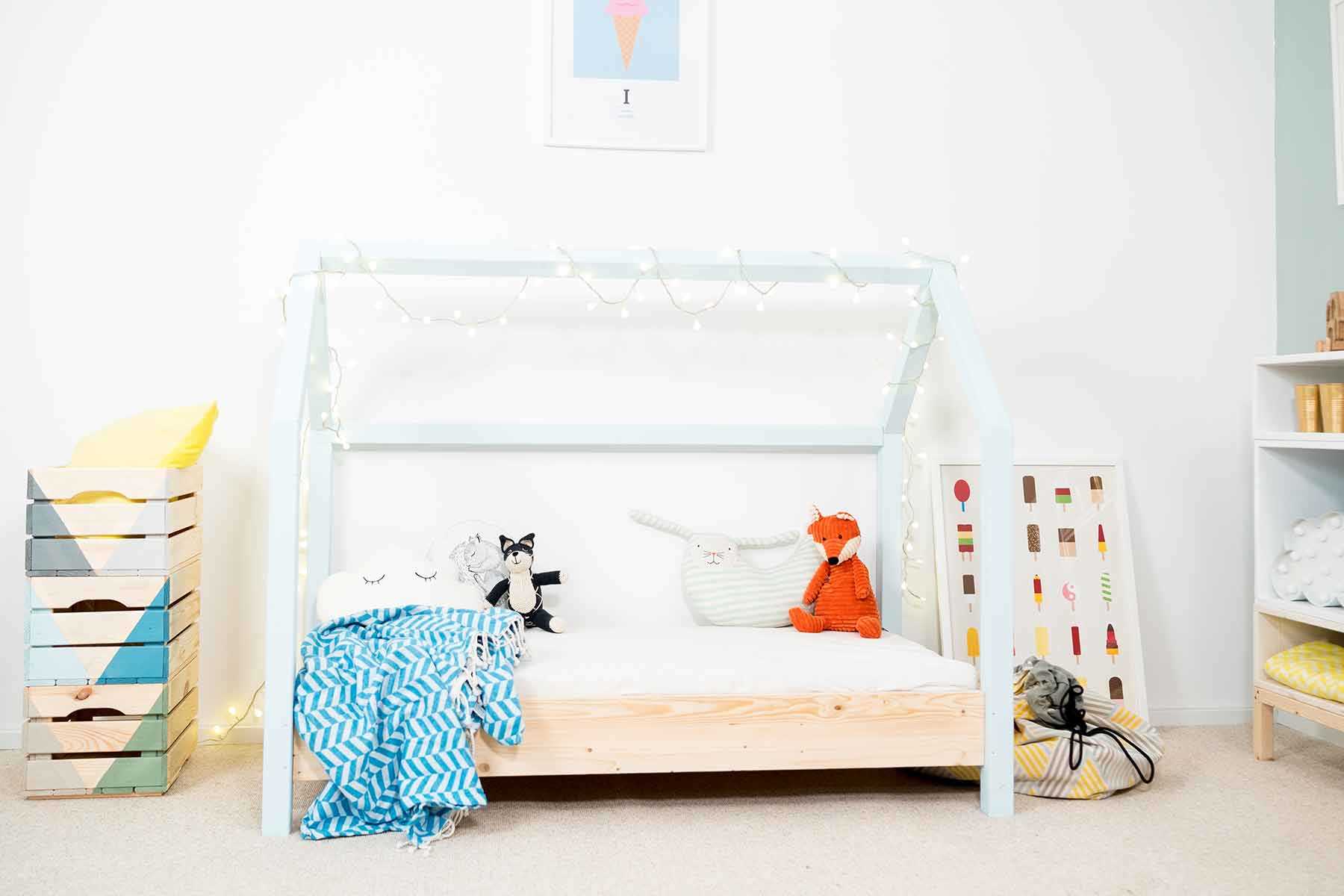 Frontansicht des spielhausförmigen Kinderbett Moritz mit hellblauen Balken.