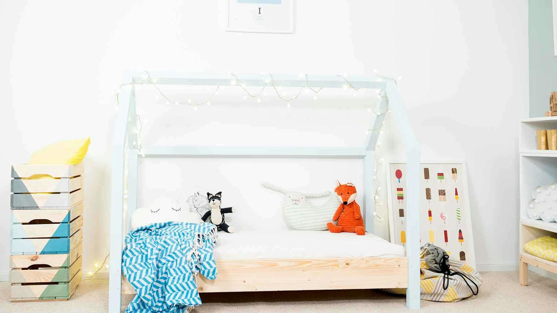 Frontansicht des spielhausförmigen Kinderbett Moritz mit hellblauen Balken.