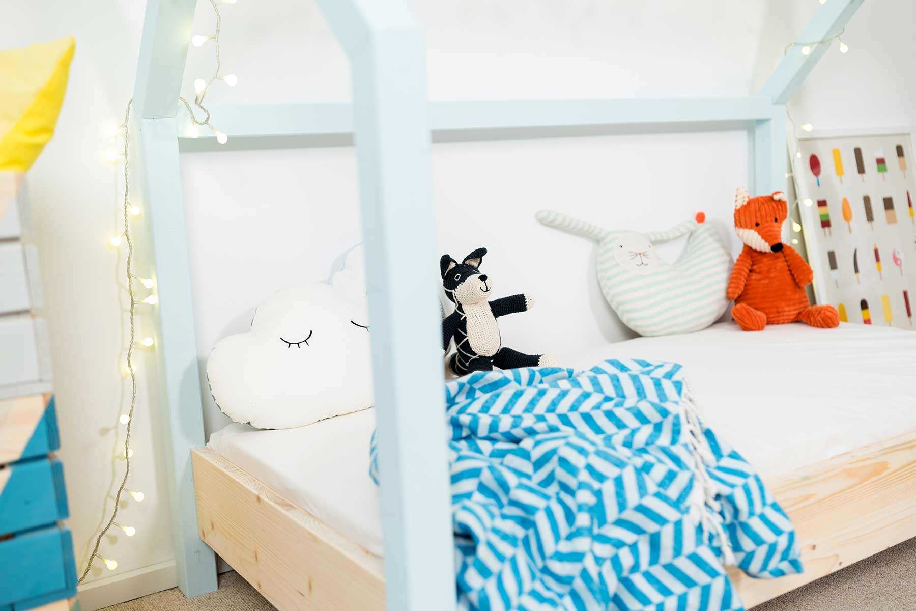 Seitliche Detailansicht des spielhausförmigen Kinderbetts Moritz mit hellblauen Balken.