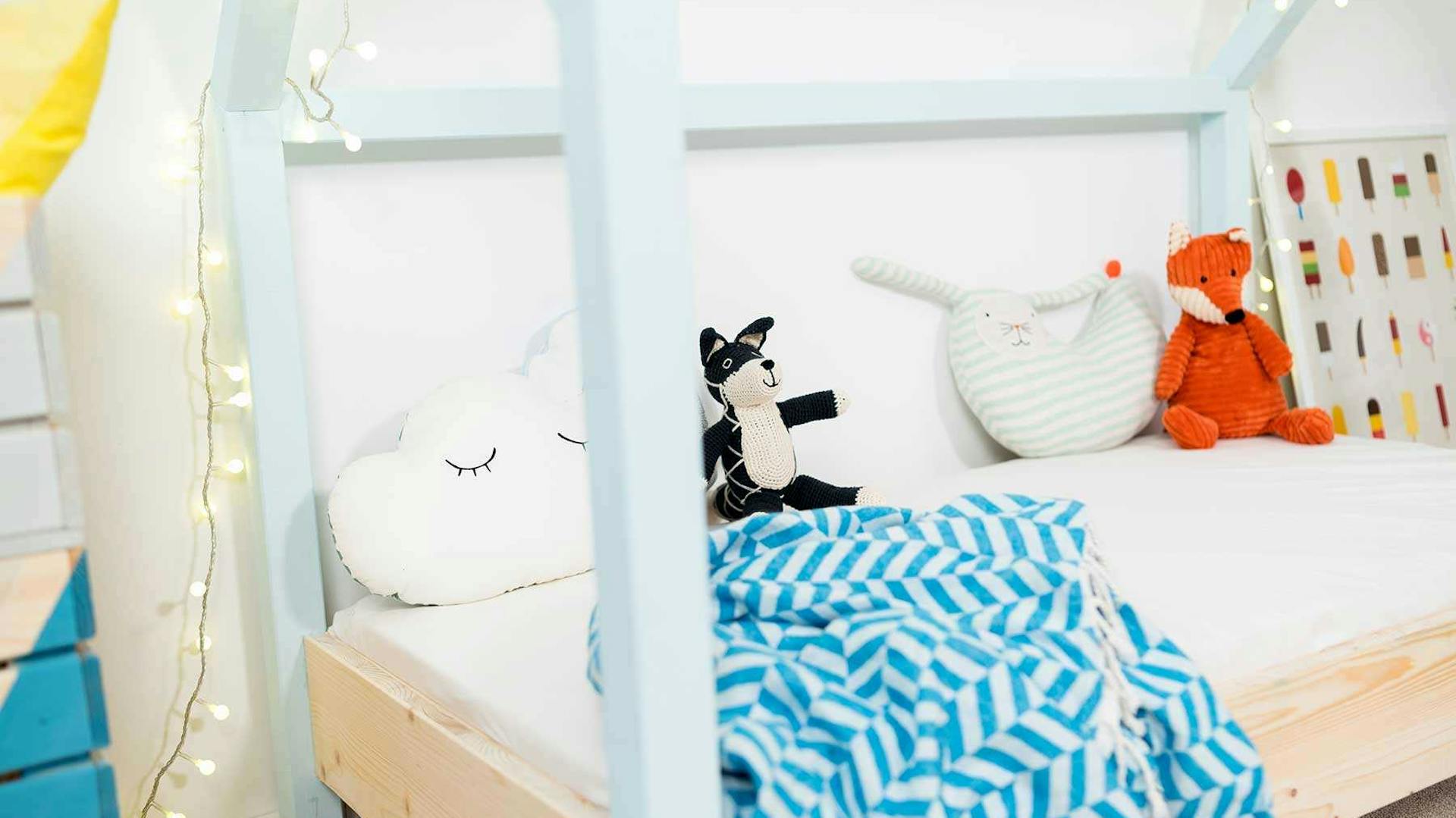 Seitliche Detailansicht des spielhausförmigen Kinderbetts Moritz mit hellblauen Balken.