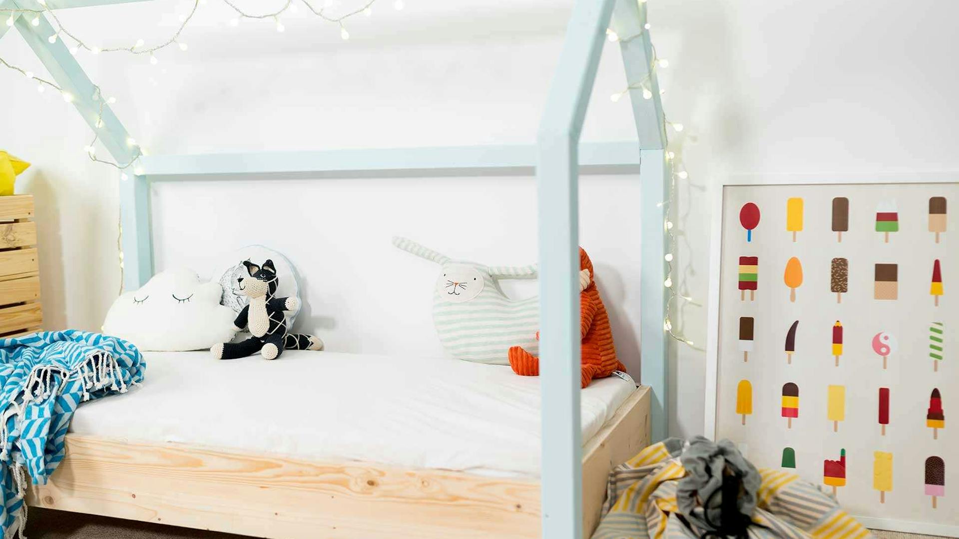 Seitliche Ansicht auf das Kinderbett Moritz mit hellblauen Balken.