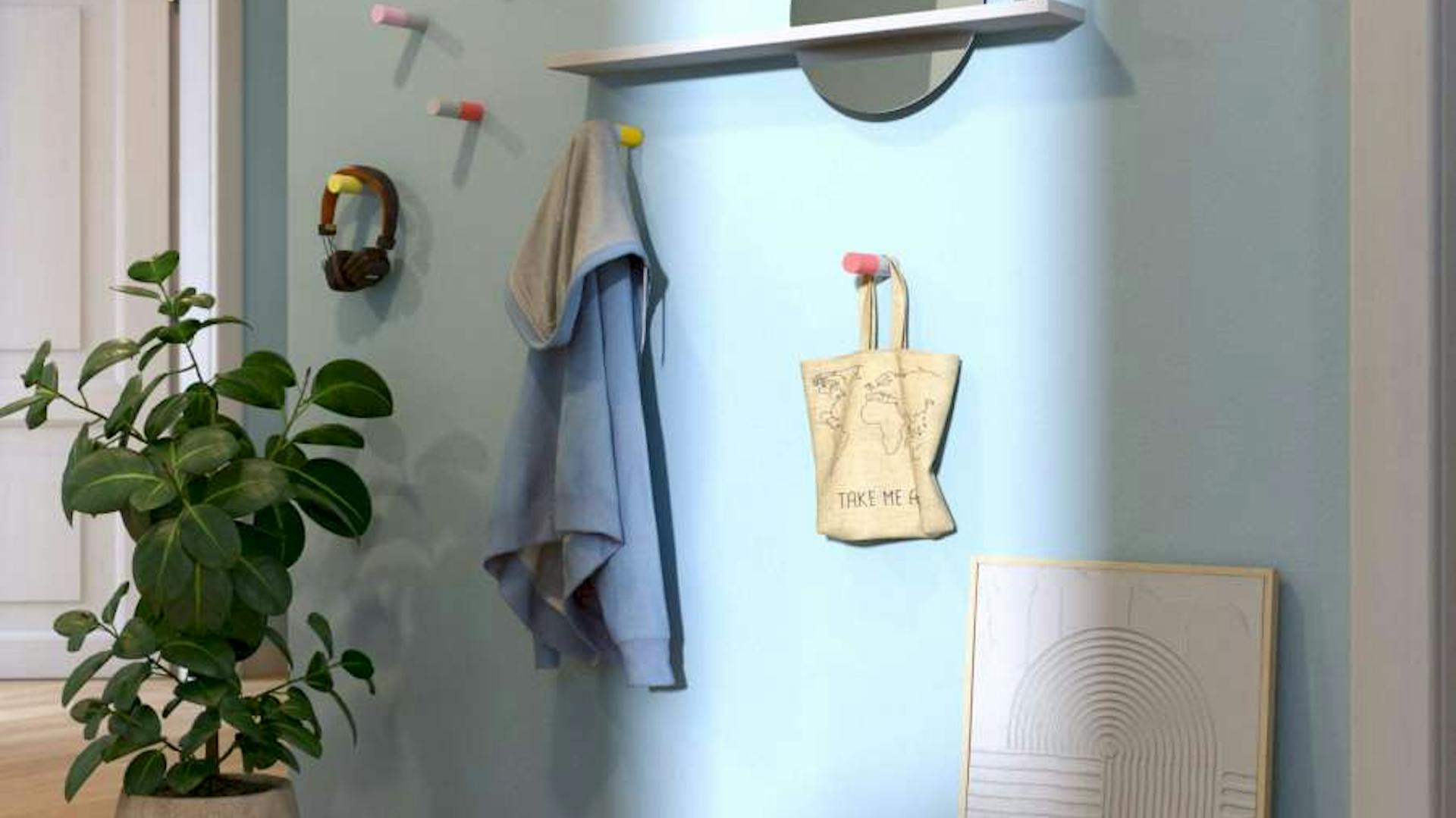 An einer hellblauen Wand hängen DIY-Wandhaken und ein Gaderobenspiegel. Davor steht eine Pflanze und ein Bild.