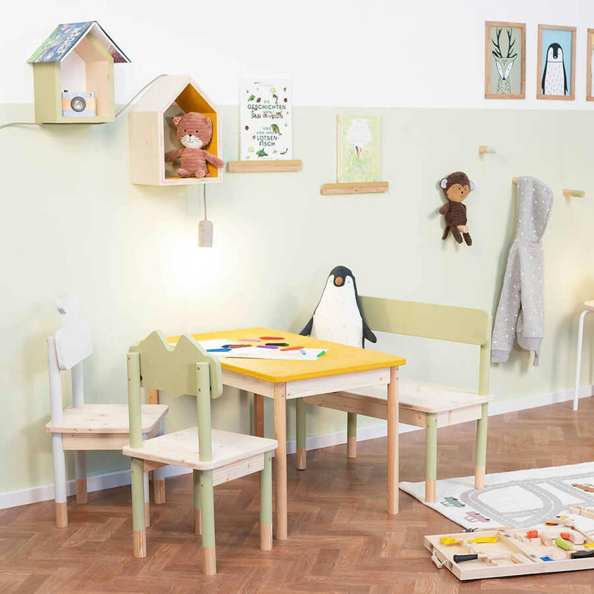 Bunte Kindersitzgruppe steht vor einer pastellgrünen Wand in einem Kinderzimmer.