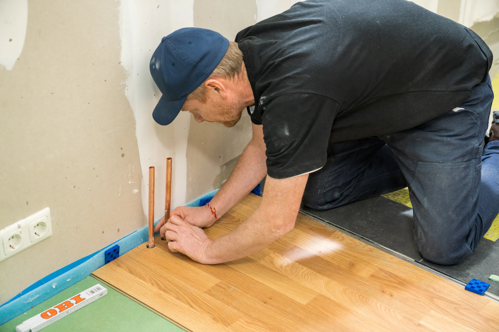 L’appassionato del fai-da-te pratica nel laminato le rientranze per i tubi di riscaldamento.