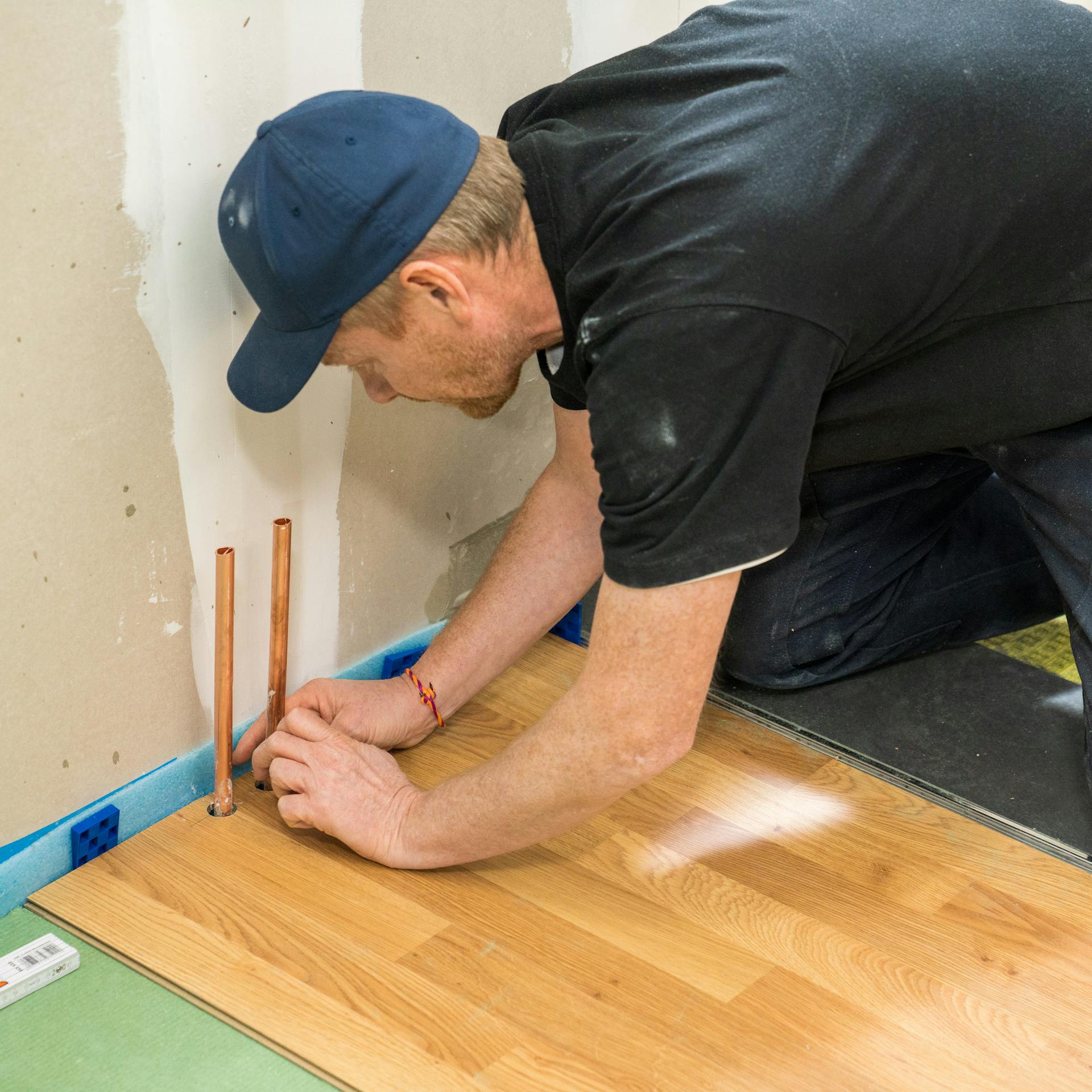 Heimwerker bohrt Aussparungen für Heizungsrohre in das Laminat.
