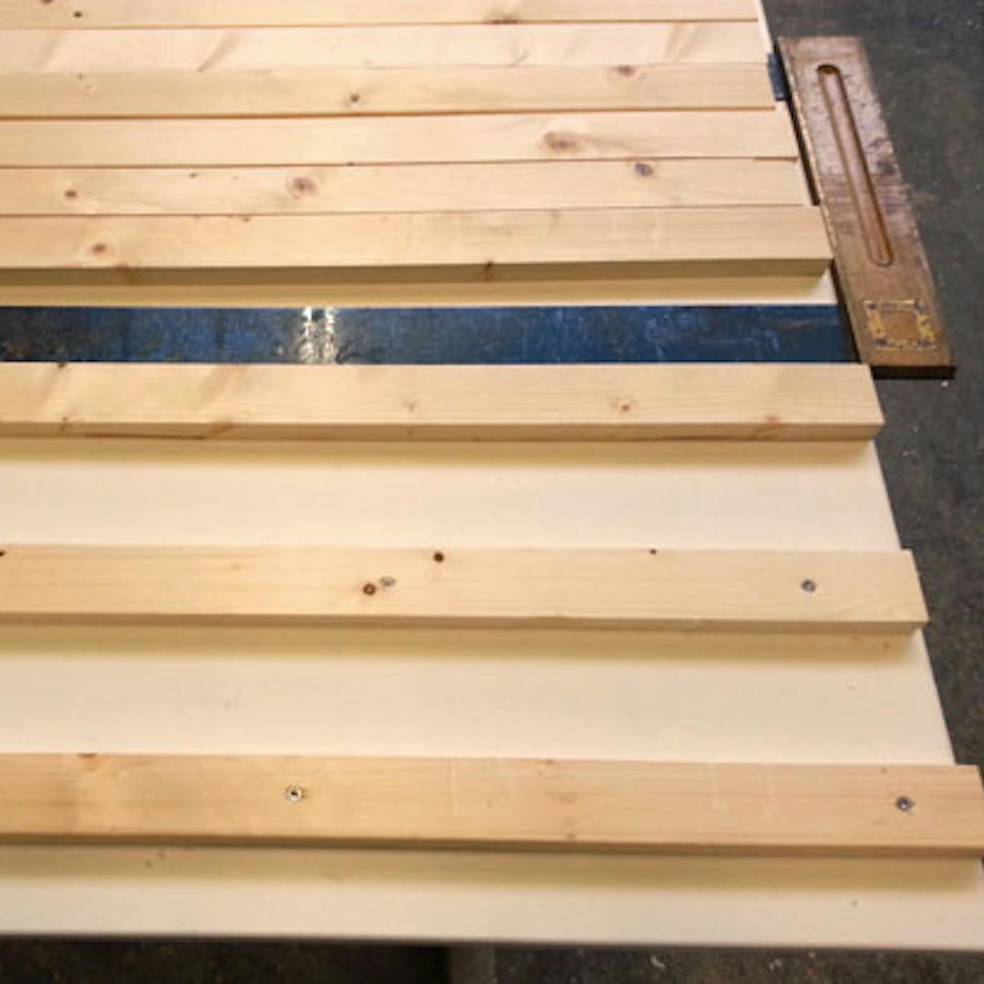 Ausrichten der Abstandshalter und Holzlatten auf der LED-Rückwand mit einem Zimmermannswinkel.