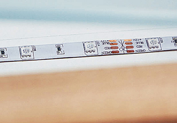 Ein LED-Streifen wird auf eine Leiste geklebt.