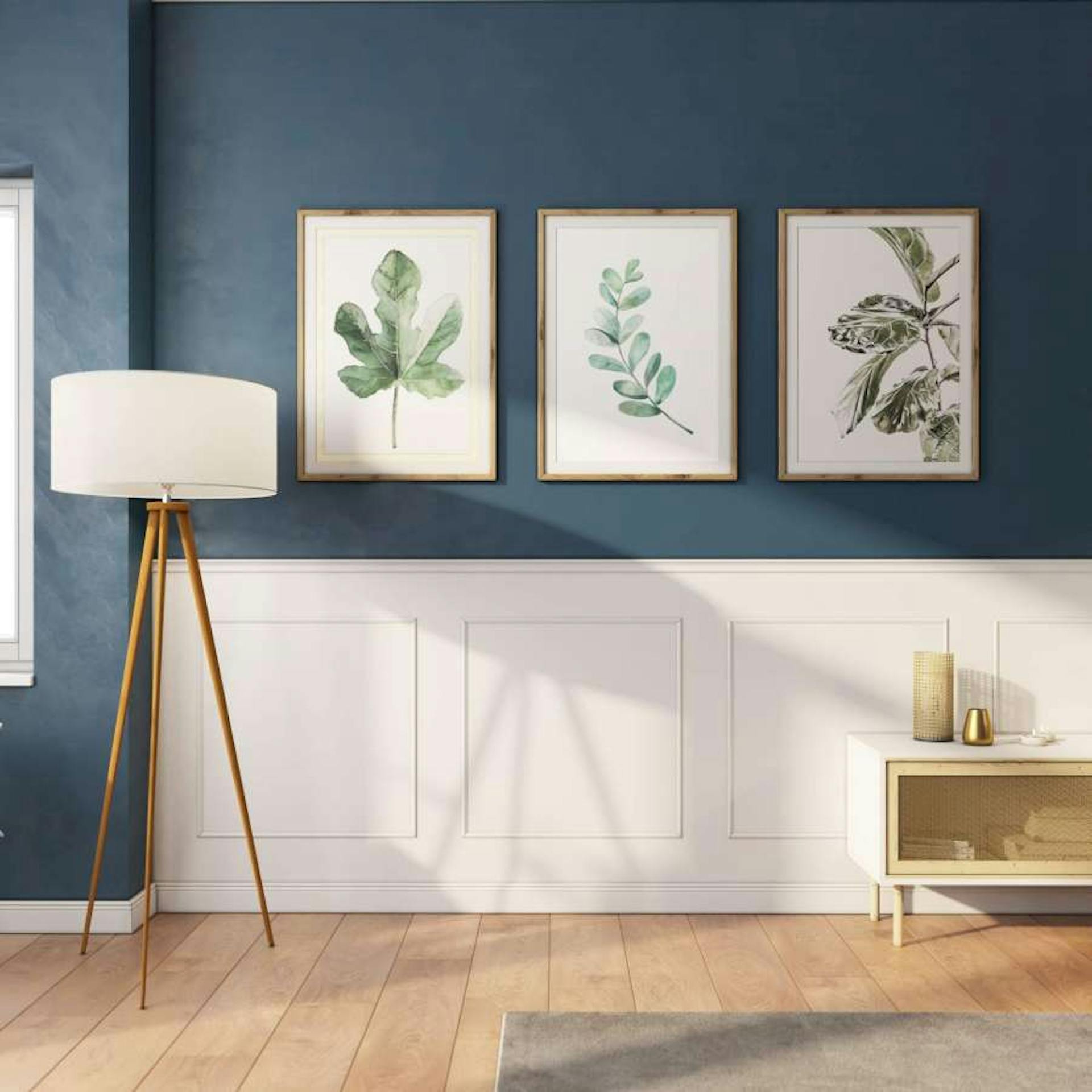 An einer blauen Wand, die zur Hälfte eine weiße Kassettierung hat, hängen Bilder von Pflanzen. Davor stehen eine Lampe und ein Regal.