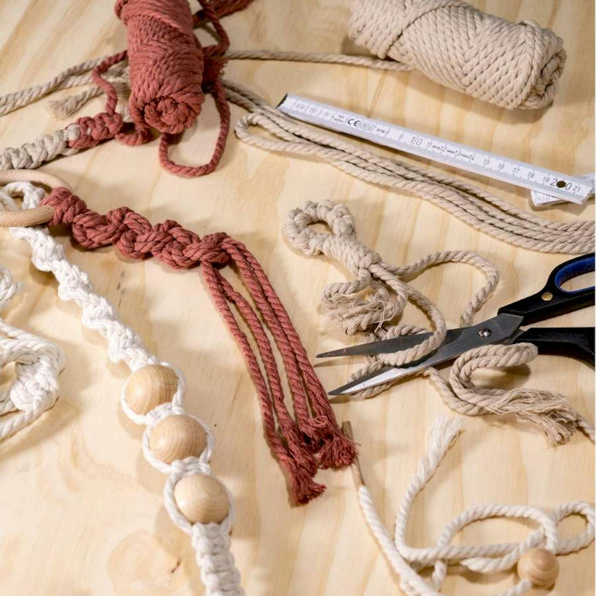 Verschiedene Makramee-Knotensammlungen neben Schere und Gliedermaßstab