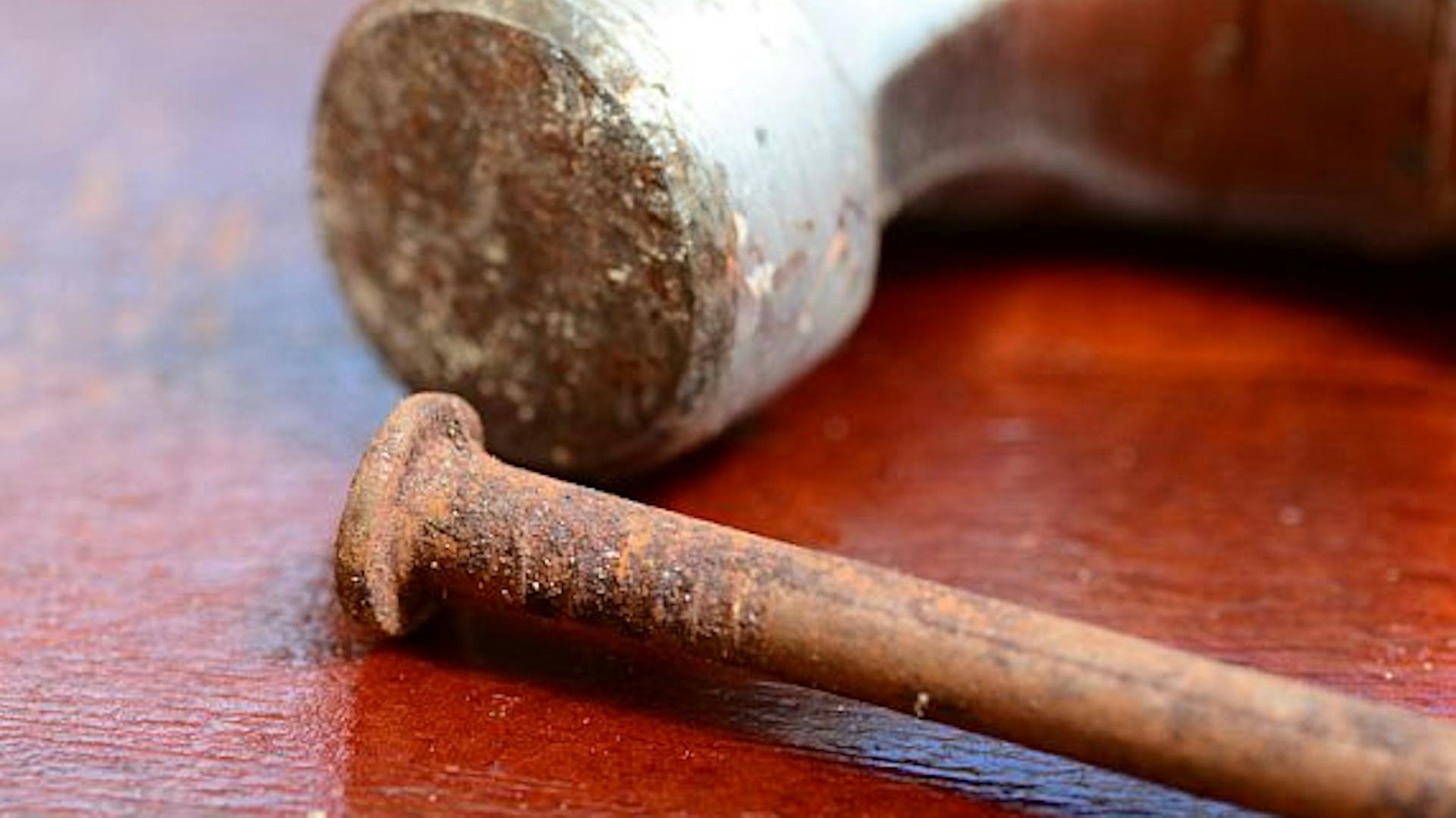 Hrdzavý klinec a hrdzavé kladivo na doske stola