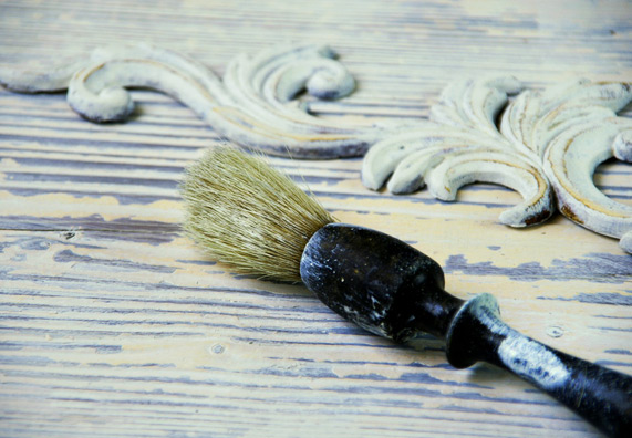 Egy ecset hever egy régi fehér bútoron.