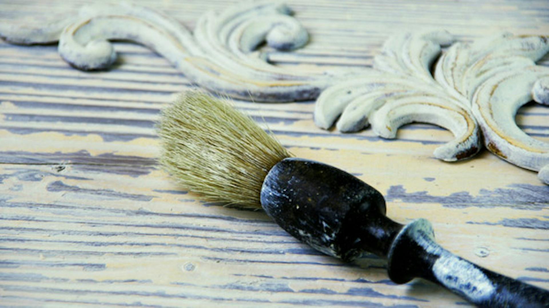 Egy ecset hever egy régi fehér bútoron.