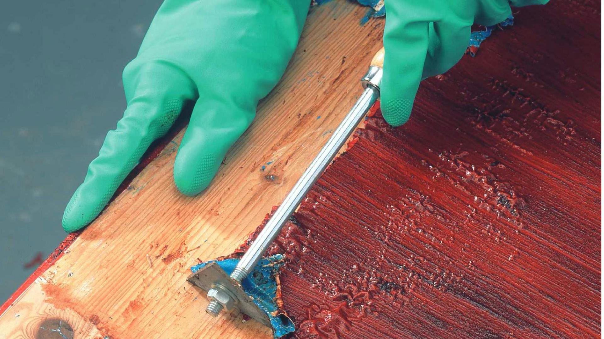 Von einem Möbelstück wird Farbe mithilfe eines Abbeizers entfernt.
