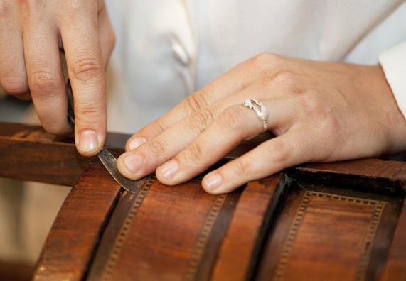 Egy ember régi furnért javít egy antik bútoron.