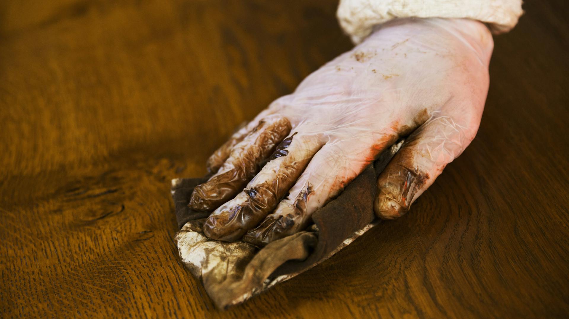 Egy ember fafelületet kezel egy régi bútordarabon.