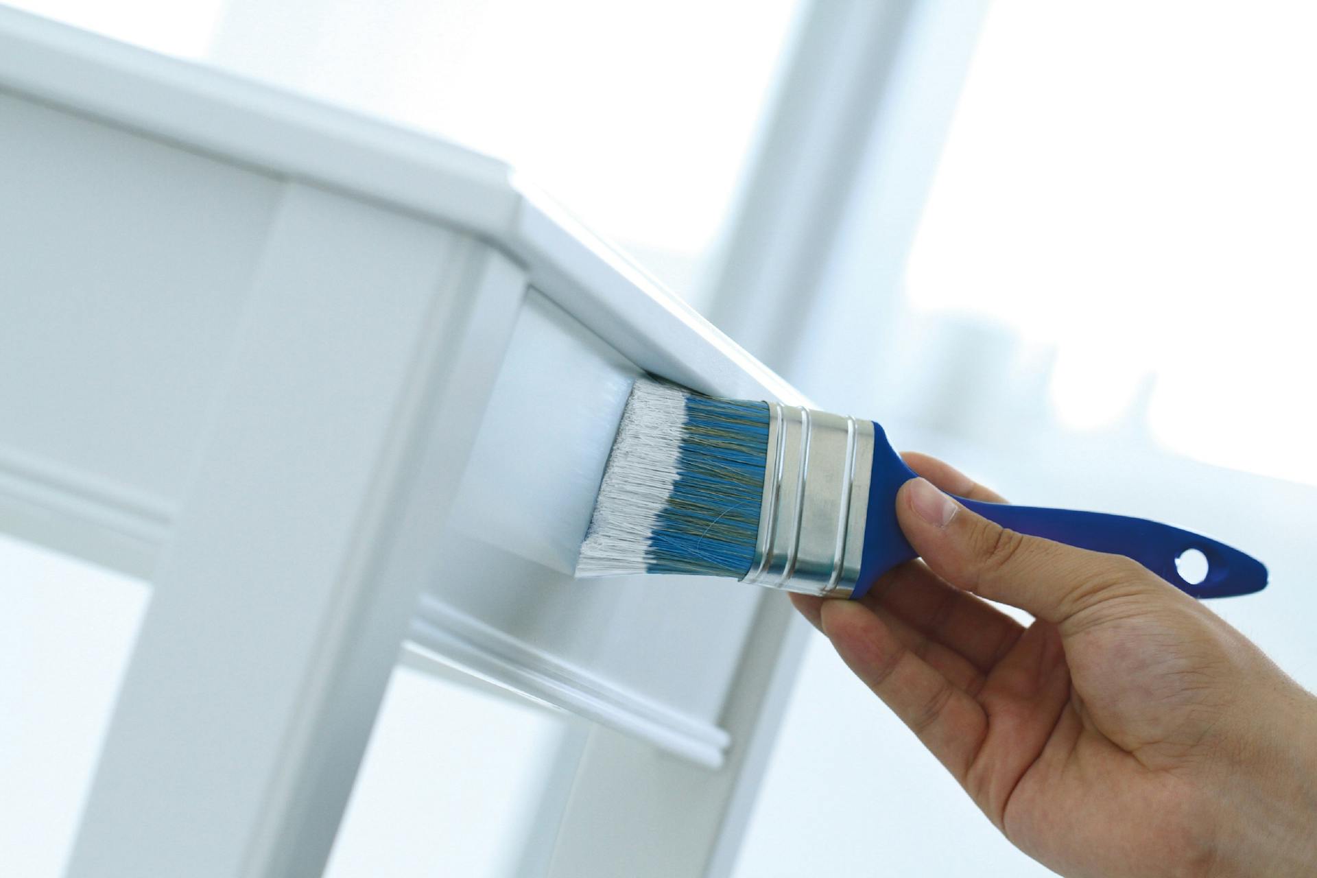 Un uomo vernicia una sedia di bianco con un pennello